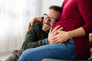 Obraz premium Beautiful pregnant woman and her handsome husband are smiling while spending time together at home
