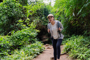 Female biologist walking in tropical forest carrying backpack and binoculars