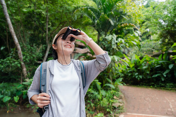 Young hiker exploring tropical forest using binoculars