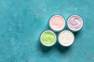 Set of cosmetic creams in jars for skin care on blue grunge background, top view
