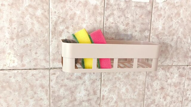 Sponges for washing dishes, a brush in a plastic container. Cleaning equipment in the kitchen.