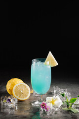 Blue Cocktail with Pineapple and Lemon Garnish on Dark Background