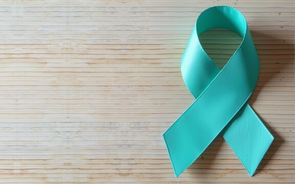 Teal awareness ribbon on wooden background, top view with space for text. Symbol of social and medical issues. High quality