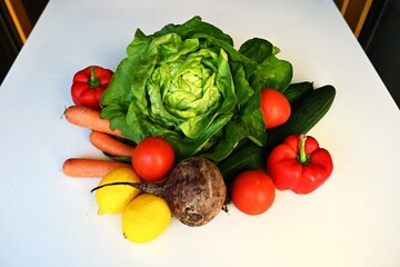 Assortment of fresh organic vegetables including lettuce, tomatoes, carrots, cucumber, beetroot, and peppers. Healthy eco-friendly produce from local sustainable farming.