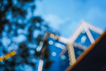 Low angle view of a blurred office building at night. Luxury real estate, urban development, and contemporary architecture against a clear blue evening sky.