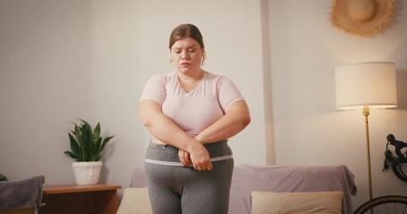 Plus size woman measures waist reacting to unsatisfactory result