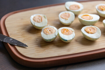 bunch of hard-boiled eggs sliced in half on a wooden cutting board