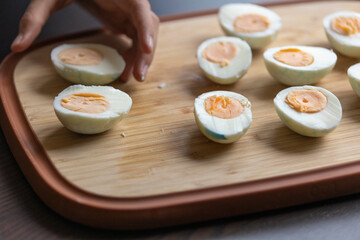 bunch of hard-boiled eggs sliced in half on a wooden cutting board