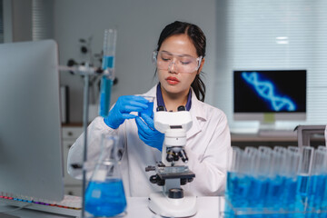 Scientist analyzing blue chemical liquid with microscope in laboratory