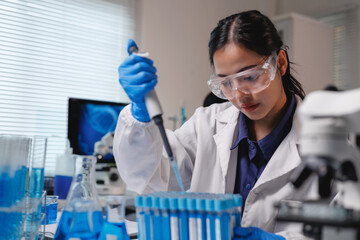 Fototapeta premium Scientist using micropipette filling test tubes in laboratory