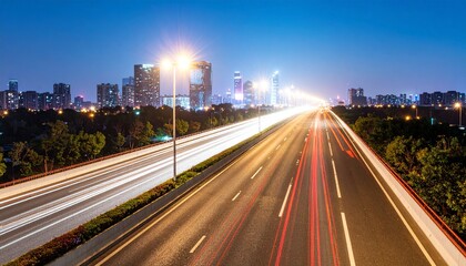 Fototapeta premium Long exposure shot of a busy highway at night with light trails from cars, leading towards a modern city skyline.