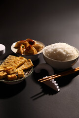 Tasty Chinese food and chopsticks on dark background