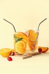 Glasses of infused water with orange slices on beige background