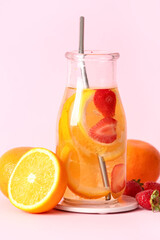 Bottle of infused water with orange slices on pink background