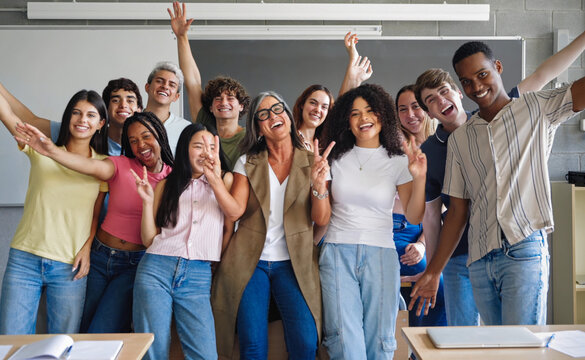 Cheerful college students with senior female professor celebrating success together at High School 