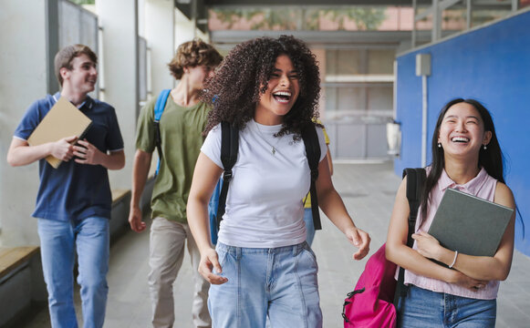 Asian and African American girl friends walking to College - Cheerful secondary school students going back to classes