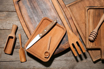 Different cutting boards, knife and spoons on wooden background