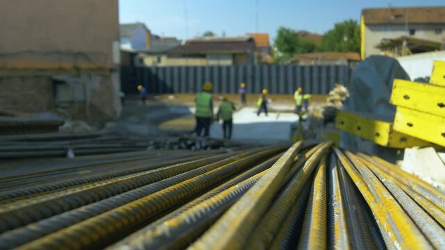A group of workers at work on a construction site, rebars in focus, close-up