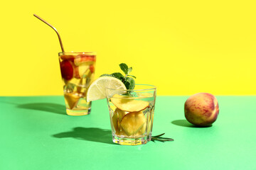 Glasses of fresh peach lemonade with mint and rosemary on colorful background