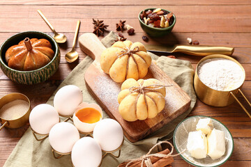 Board with pumpkin shaped buns and ingredients on wooden background