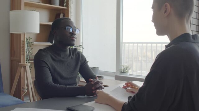 Young Black man attending job interview in modern company telling HR manager about his expectations