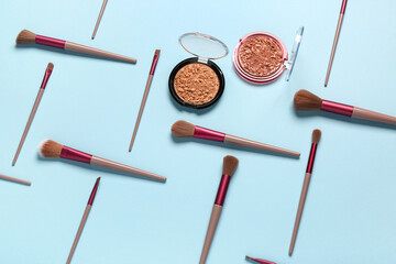 Makeup brushes and different decorative cosmetics on blue background