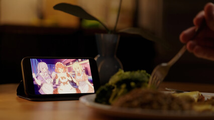 Watching Japanese anime with cute maids on smartphone while eating meal in kitchen