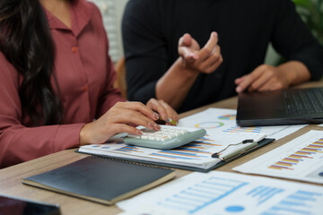 Businesswoman using calculator during corporate meeting with charts and graphs