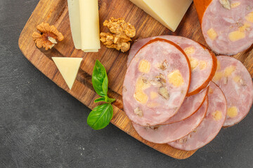 Sliced sausage with cheese, walnuts, and basil served on rustic wooden board. top view. copy space