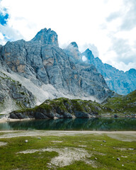 A stunning view of a calm alpine lake reflecting a majestic, rugged mountain range under a cloudy sky