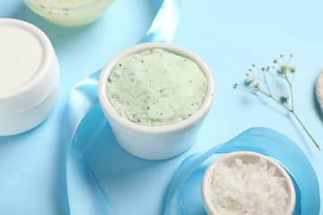 Scrub with sea salt, cream and ribbon on blue background. Body massage concept