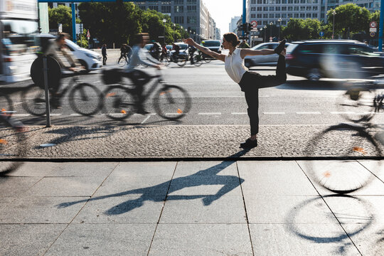 Young businesswoman practising yoga in the city at rush hour, Berlin, Germany