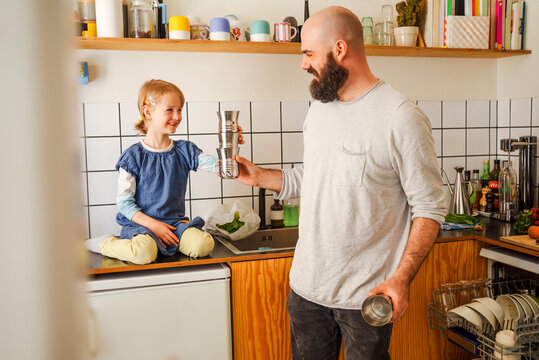 Smiling girl playing with father in kitchen at home
