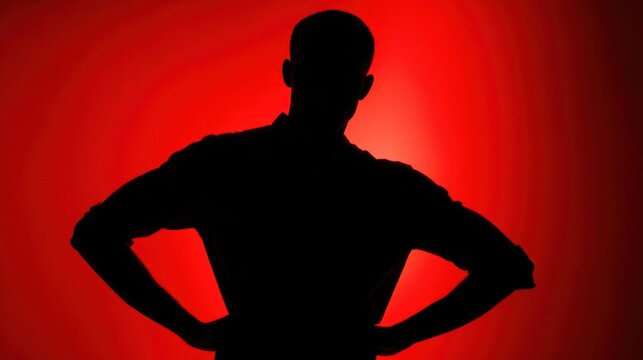 Silhouette of a man with hands on hips against a red background