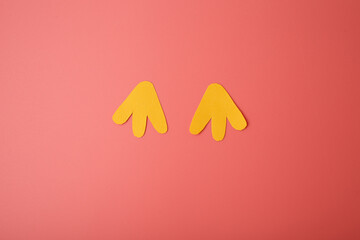 Obraz premium simple shapes Feet, Two yellow paper cut-outs positioned against pink background, top down view, close up, Minimalist and playful, using basic shapes and bold colors to create bird figure