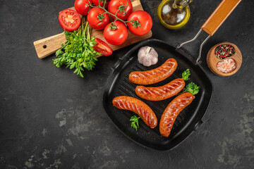 Grilled sausages with fresh tomatoes, herbs, garlic, and spices on dark kitchen table. top view. copy space