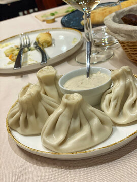 Plate of khinkali dumplings with dipping sauce served in a restaurant setting in Silvi, Abruzzo, Italy, showcasing traditional Georgian cuisine