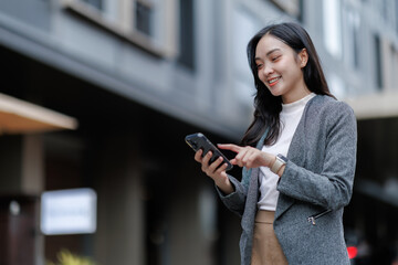 Smiling businesswoman using smartphone on city street
