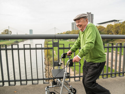 Playful senior man with wheeled walker on bridge
