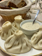 Delicious khinkali dumplings served with a creamy sauce, accompanied by a basket of bread, ready to be enjoyed in a restaurant setting