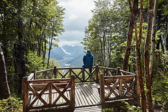 Chile, Chaiten, Parque Pumalin, man sitting on observation deck looking at glacier