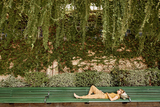 Woman lying on bench in park