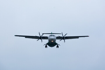 Head-on view of a turboprop passenger airplane on final approach for landing against an overcast sky. A powerful concept for aviation, regional travel, business logistics, and arrival.