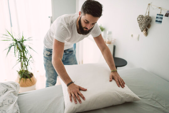 Young man making the bed at home