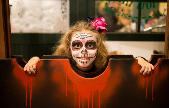 Blond little girl with sugar skull makeup at Halloween