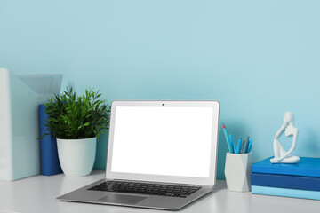 Modern workplace with laptop, stationery and books in light office