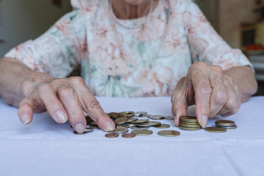 Senior woman stacking coins on table at home