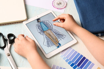 Female fashion designer drawing on tablet sketch of male clothes on light grunge background