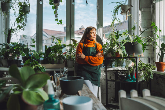 Thoughtful botanist leaning on window sill in plant store
