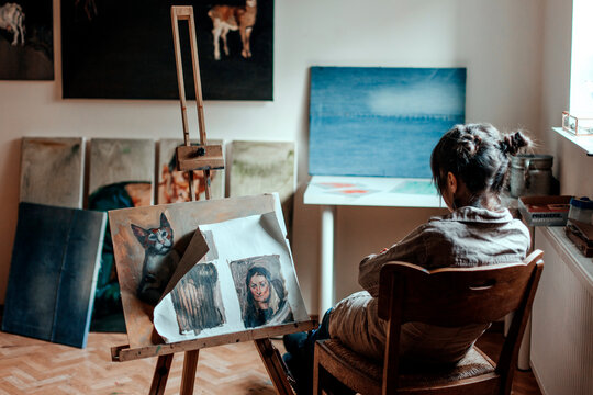 Rear view of a female artist sitting in her studio in front of a painting
